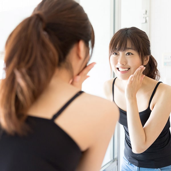 A young woman looking in the mirror after her botox treatment