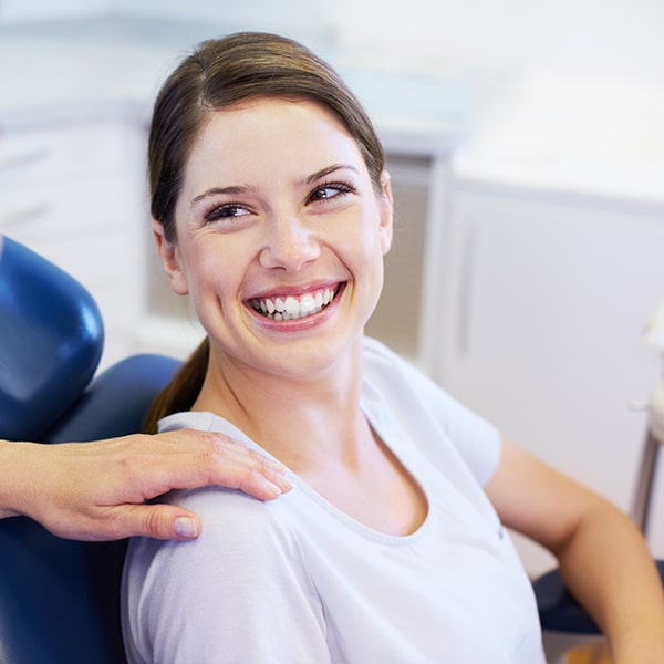 The dentist placing his hand on the shoulder of a smiling woman